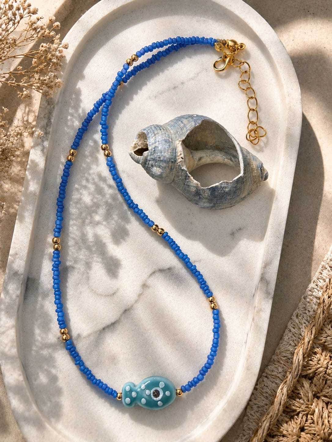 Overzicht van de Azure Fish blauwe beach kralenketting met turquoise glazen visje op een zomerse ondergrond.