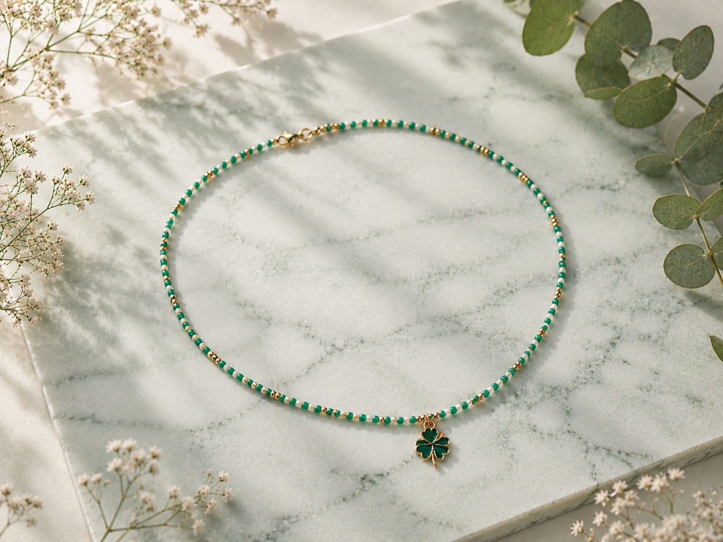 Overzicht van de Lucky Clover handgemaakte groene kralenketting met klaverbedel op een marmeren ondergrond.