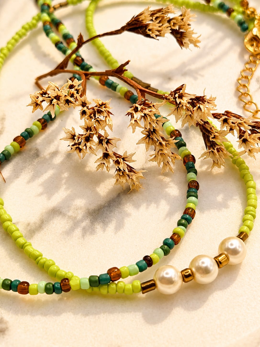 Close-up van een handgemaakte dubbele groene kralenketting met drie parels en fijne glaskralen.
