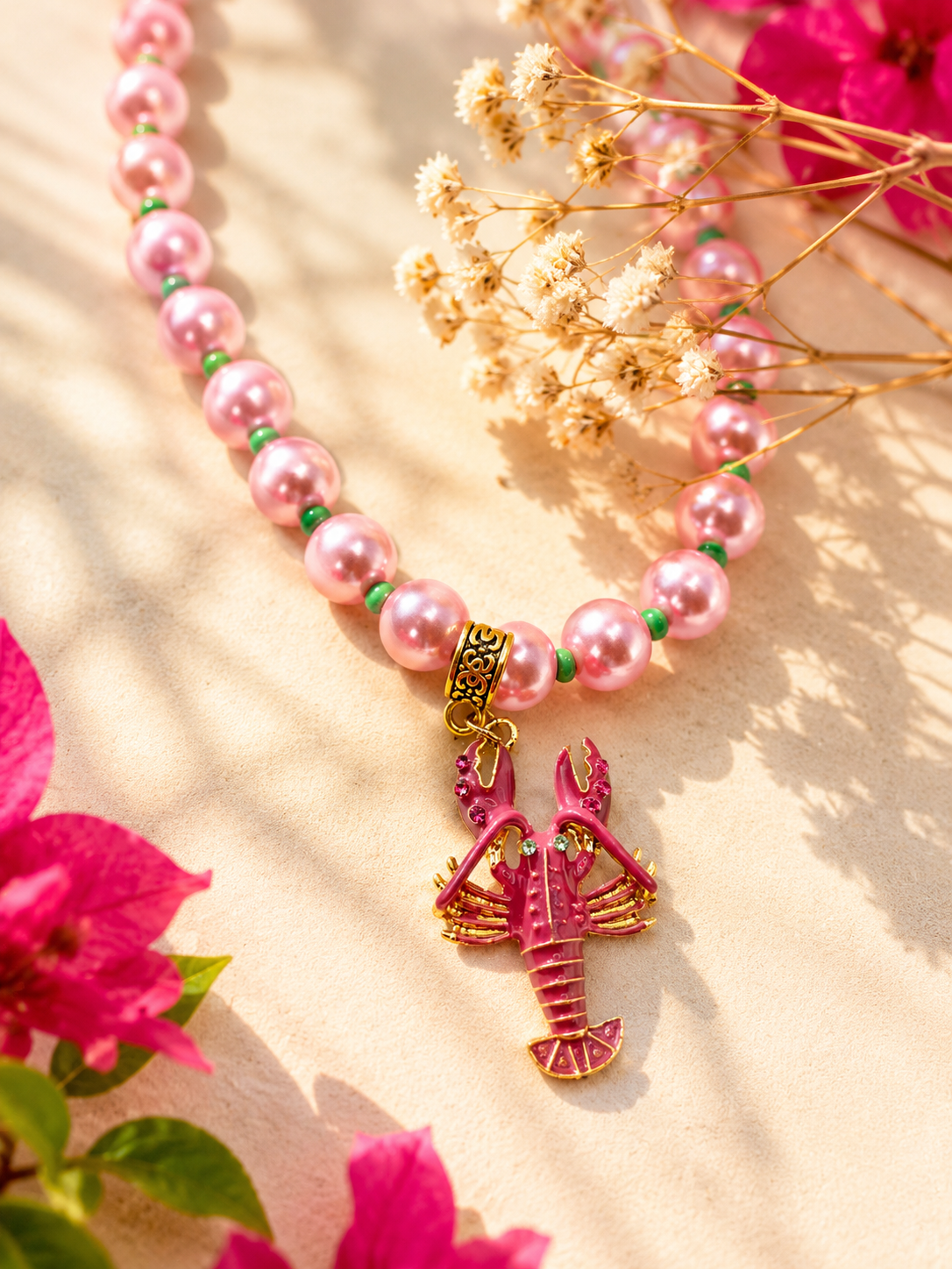 Close-up van een handgemaakte roze kralenketting met goudkleurige kreeft bedel en glanzende kralen