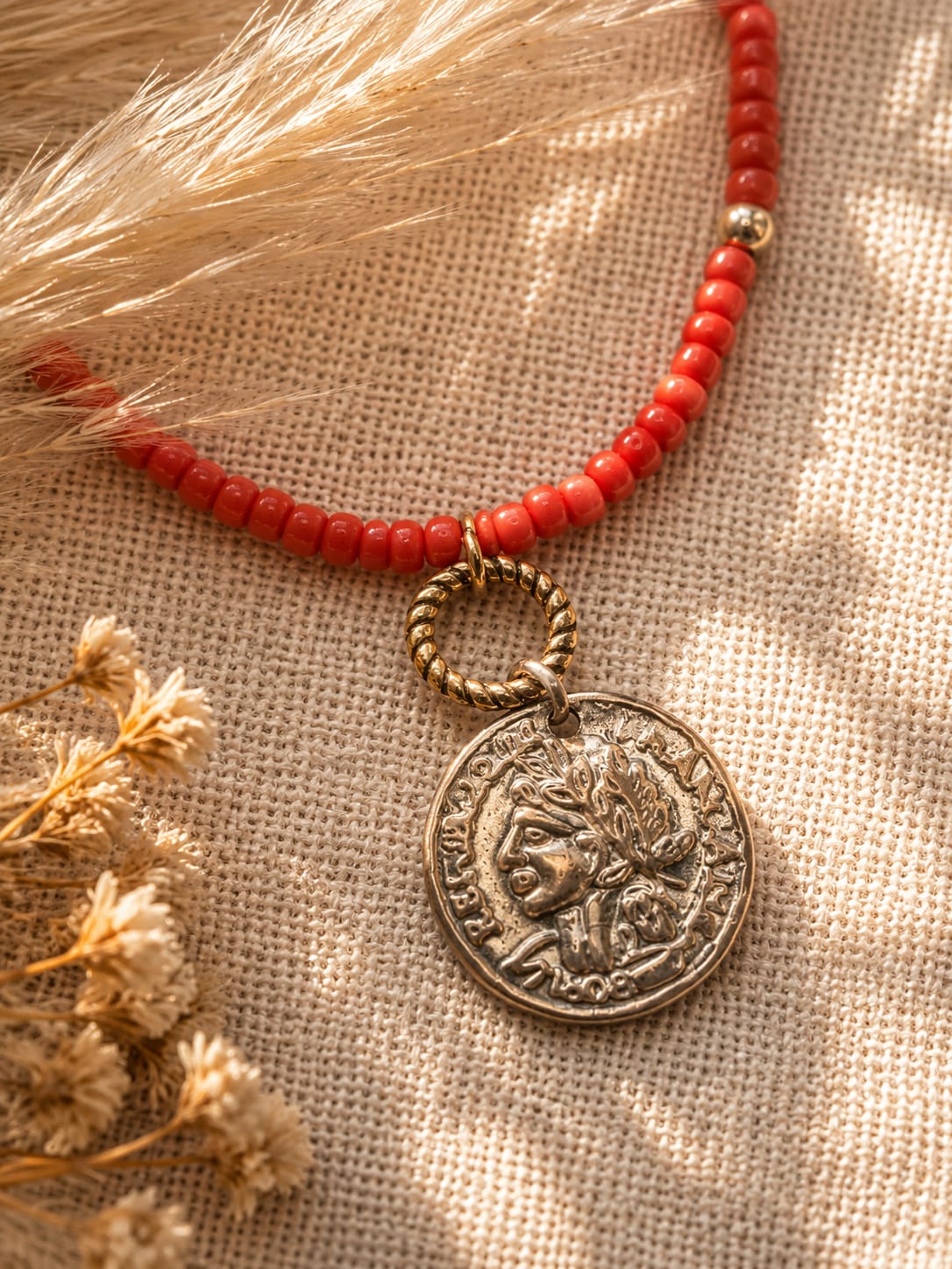 vintage muntbedeltje van een koraalrode bali stijl ketting