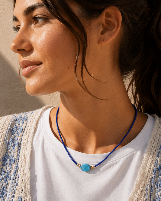 Model draagt een handgemaakte blauwe kralenketting met turquoise sierkraal.