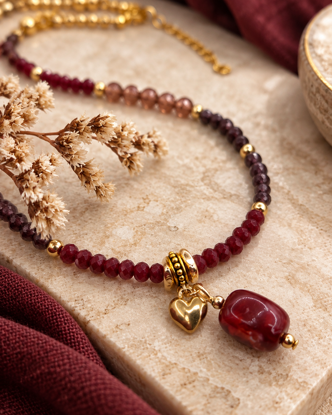Detail van Burgundy Bloom kralenketting met rode bedel en goudkleurig hartje