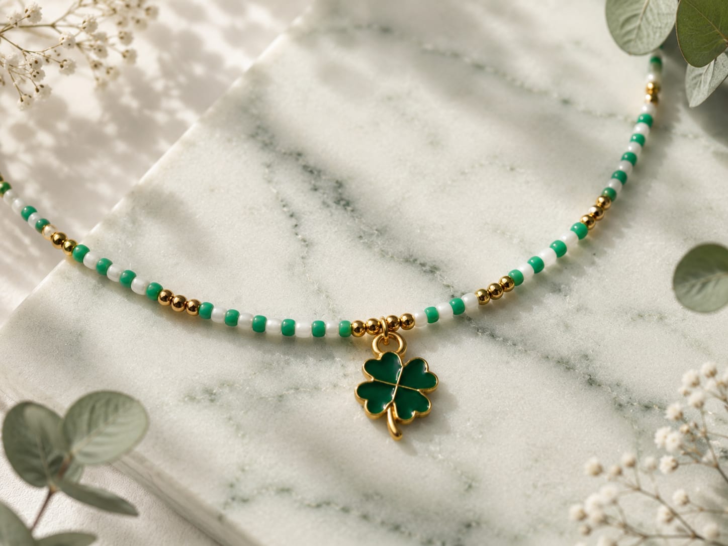 Detailfoto van de Lucky Clover groene boho kralenketting met groene klaverbedel, witte glaskralen en goudkleurige accenten.