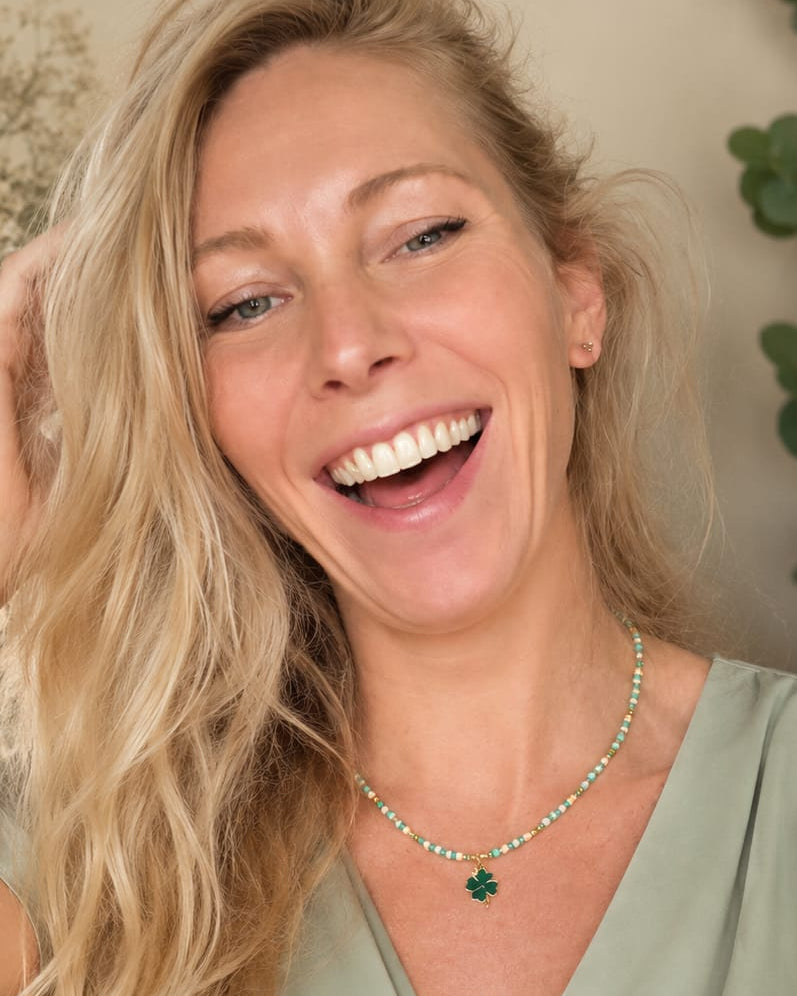 Model draagt de Lucky Clover groene boho kralenketting met klaverbedel en goudkleurige accenten.