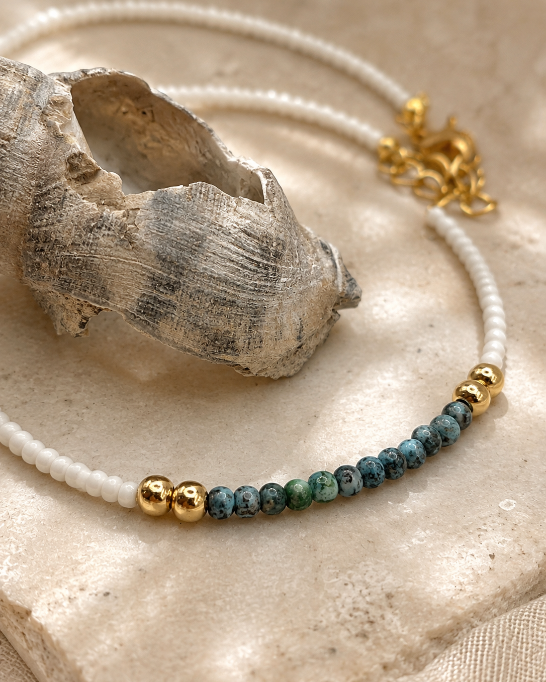 Detail van Pearl Coast witte kralenketting met blauwgroene en goudkleurige kralen