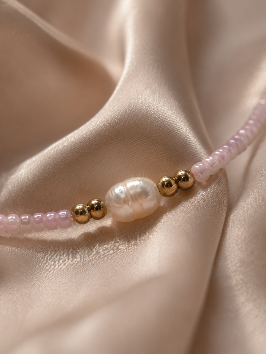 Detail van een zoetwaterparel in een handgemaakte roze kralenketting.