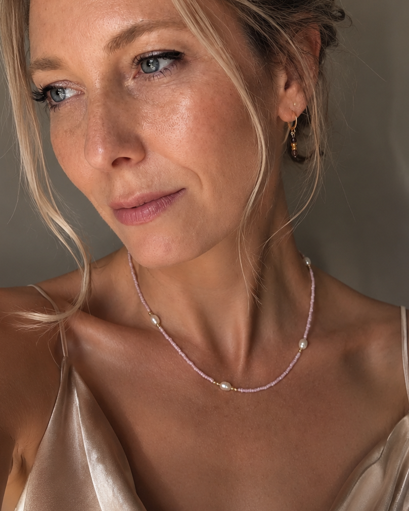 Handgemaakte roze kralenketting met zoetwaterparels gedragen door model.