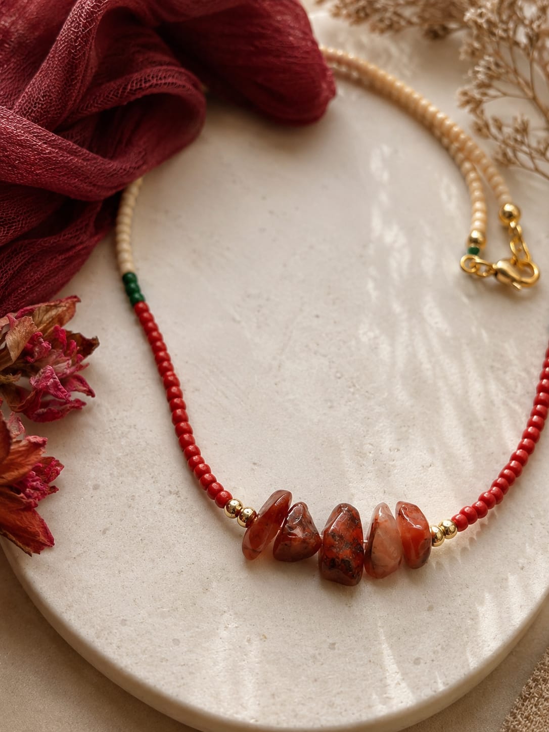 Detailfoto van de Siena rode agaat kralenketting met natuurlijke rode agaat stenen en goudkleurige kralen.