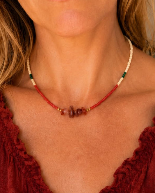 Model draagt de Siena handgemaakte rode agaat kralenketting met zandkleurige, rode en groene kralen en goudkleurige accenten.