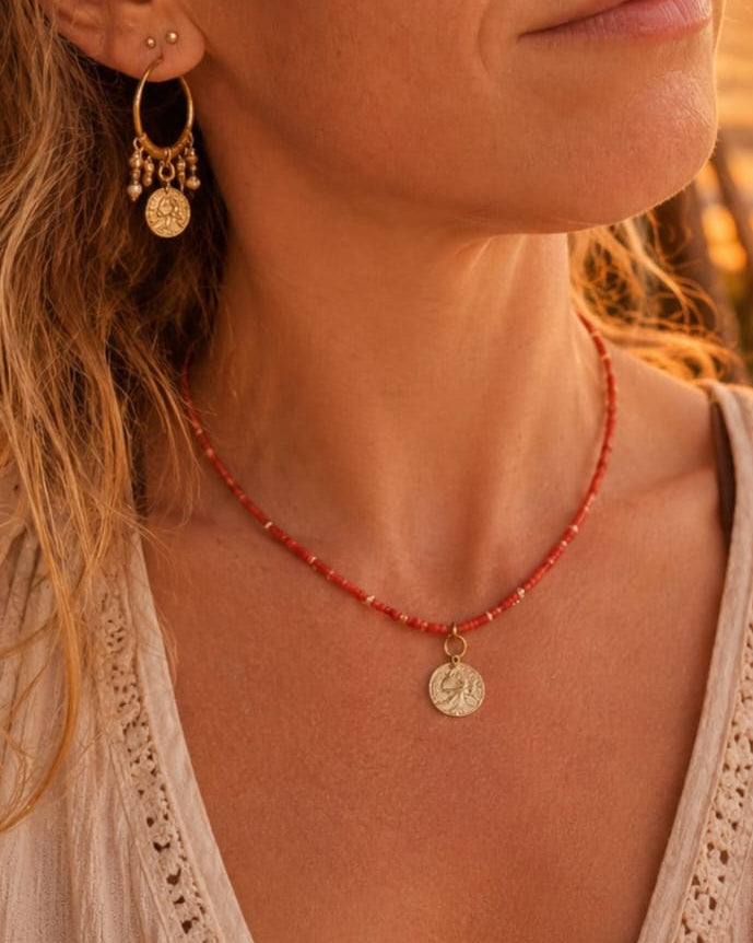 Rode ketting met muntbedel gedragen op zongebruinde huid.
