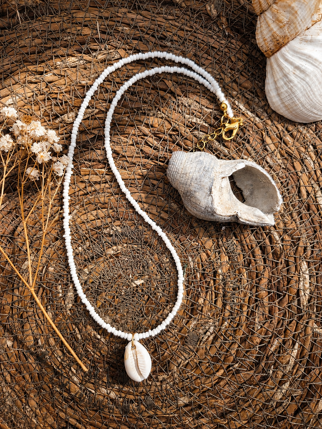 strandketting met witte kralen een een subtiel schelpje op een houten achtergrond